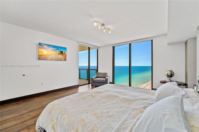 16275 Collins Ave Unit 2101, Sunny Isles Beach, FL 33160 - bedroom featuring wood finished floors, access to outside, a water view, baseboards, and a textured ceiling
