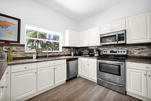 4007 Turquoise Trl, Weston, FL 33331 - kitchen with stainless steel appliances, a sink, dark wood-type flooring, backsplash, and white cabinetry