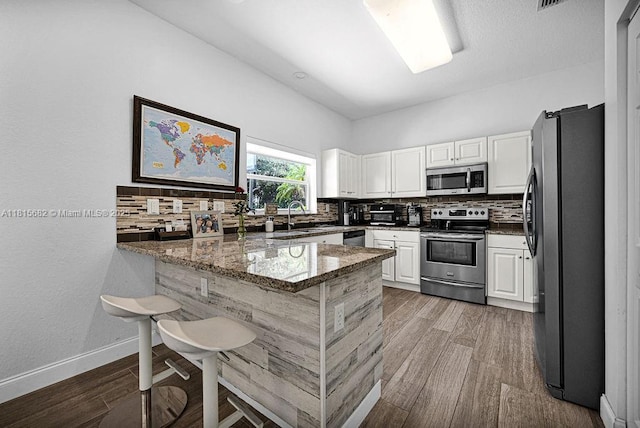 4007 Turquoise Trl, Weston, FL 33331 - kitchen with appliances with stainless steel finishes, a peninsula, backsplash, white cabinets, and stone counters