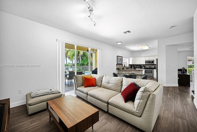 4007 Turquoise Trl, Weston, FL 33331 - living room with baseboards, a textured ceiling, dark wood-style flooring, and rail lighting