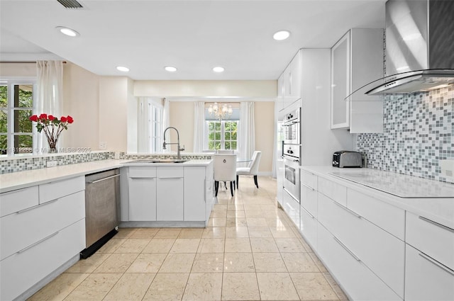 2124 Fisher Island Dr Unit 2124, Miami Beach, FL 33109 - kitchen with wall chimney exhaust hood, stainless steel appliances, a chandelier, decorative backsplash, and white cabinets