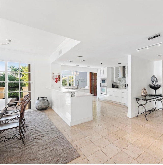 2124 Fisher Island Dr Unit 2124, Miami Beach, FL 33109 - kitchen featuring a peninsula, backsplash, white cabinets, plenty of natural light, and crown molding