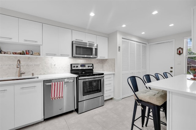 3301 S Palm Aire Dr Unit 106, Pompano Beach, FL 33069 - kitchen with appliances with stainless steel finishes, a sink, a breakfast bar area, light countertops, and backsplash