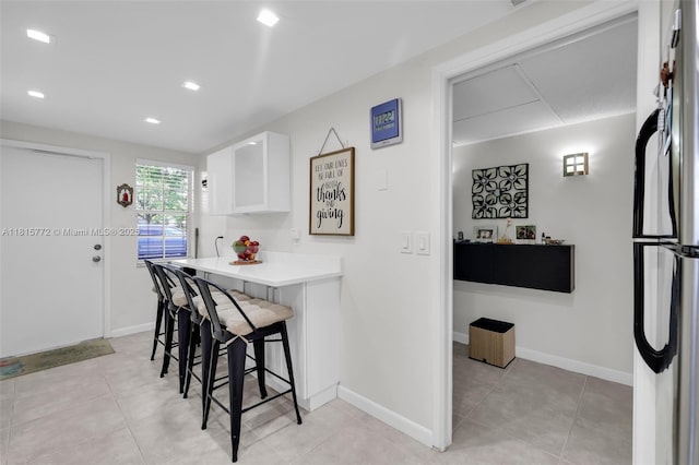 3301 S Palm Aire Dr Unit 106, Pompano Beach, FL 33069 - kitchen featuring a kitchen breakfast bar, white cabinets, freestanding refrigerator, light countertops, and baseboards