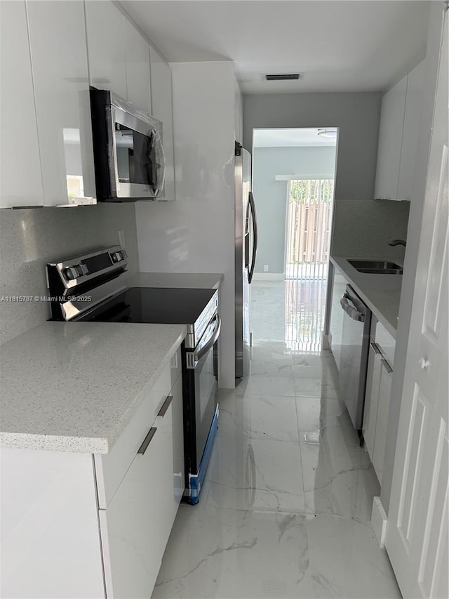 8211 NW 8th St Unit 2, Plantation, FL 33324 - kitchen with stainless steel appliances, light marble finish floors, white cabinetry, a sink, and modern cabinets