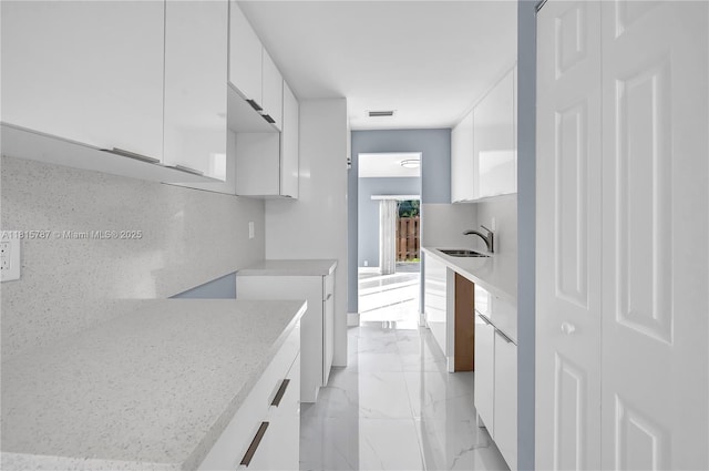 8211 NW 8th St Unit 2, Plantation, FL 33324 - kitchen with white cabinetry, modern cabinets, light marble finish flooring, a sink, and light countertops