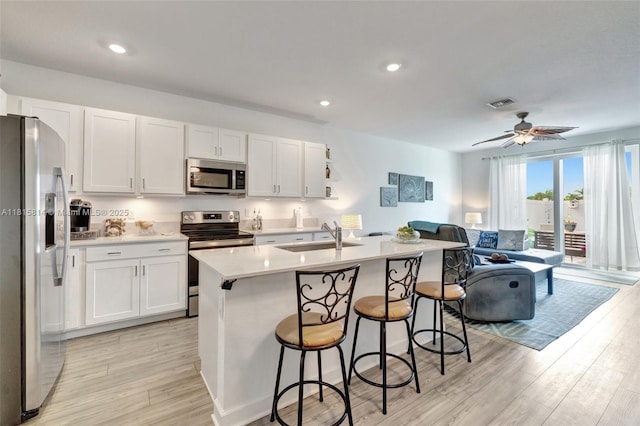 680 SE Lake Falls St, Port St Lucie, FL 34984 - kitchen with stainless steel appliances, a sink, light wood-type flooring, a breakfast bar area, and recessed lighting