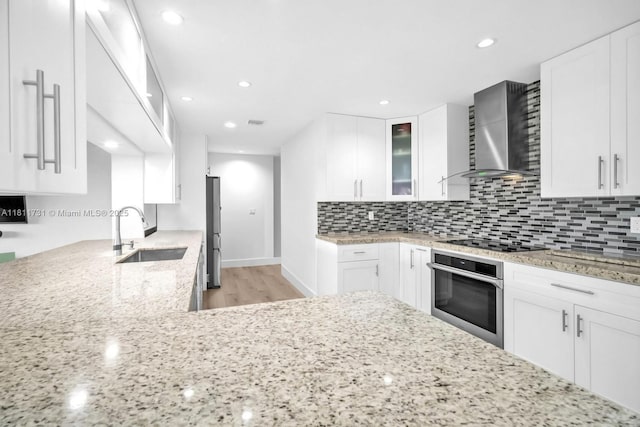 13711 SW 29th St, Davie, FL 33330 - kitchen featuring stainless steel appliances, a sink, wall chimney range hood, light stone counters, and light wood-type flooring