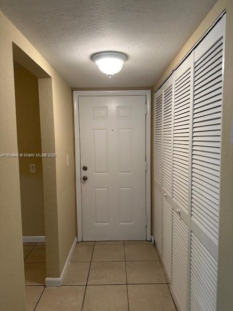9001 SW 77th Ave Unit C705, Miami, FL 33156 - corridor with light tile patterned floors, a textured ceiling, and baseboards