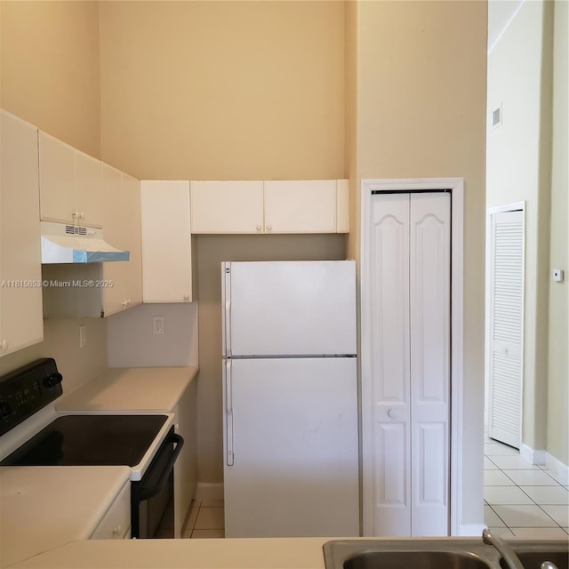 1666 SE 27th Ct Unit 205, Homestead, FL 33035 - kitchen with freestanding refrigerator, under cabinet range hood, range with electric cooktop, light tile patterned floors, and a high ceiling