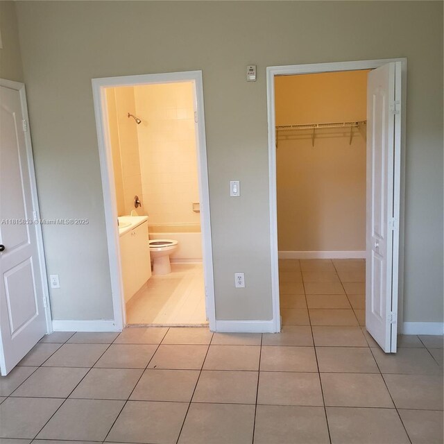 1666 SE 27th Ct Unit 205, Homestead, FL 33035 - unfurnished bedroom with light tile patterned floors, a closet, baseboards, and ensuite bath