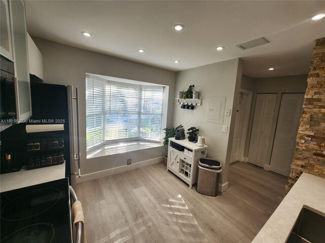 10875 NW 8th St, Pembroke Pines, FL 33026 - kitchen featuring range with electric stovetop, light wood-type flooring, light countertops, baseboards, and white cabinetry