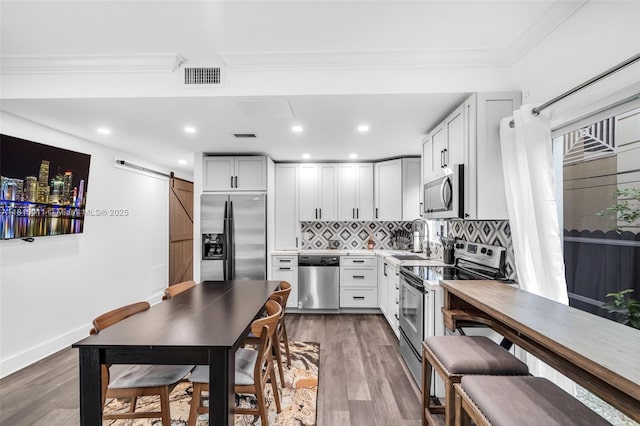3145 Day Ave Unit 1, Miami, FL 33133 - kitchen with appliances with stainless steel finishes, a barn door, a sink, backsplash, and ornamental molding