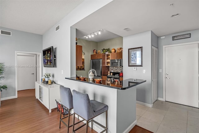 2775 NE 187th St Unit Ph6, Aventura, FL 33180 - kitchen with appliances with stainless steel finishes, a kitchen bar, a peninsula, dark countertops, and baseboards