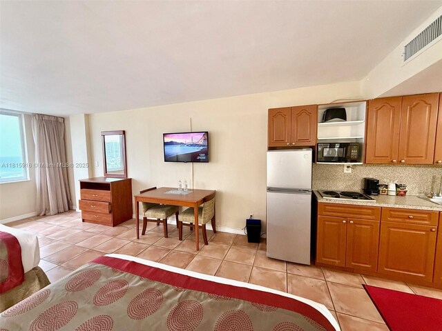 19201 Collins Ave Unit 1019, Sunny Isles Beach, FL 33160 - kitchen with freestanding refrigerator, black microwave, light tile patterned flooring, and electric stovetop