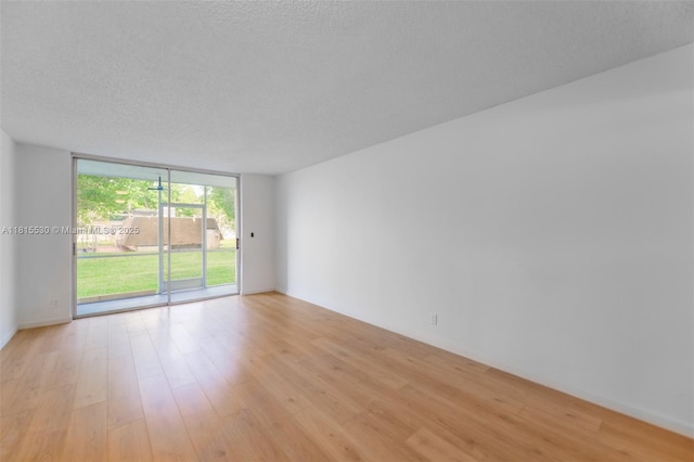 9601 Sunrise Lakes Blvd Unit 106, Sunrise, FL 33322 - spare room featuring floor to ceiling windows, light wood finished floors, and a textured ceiling