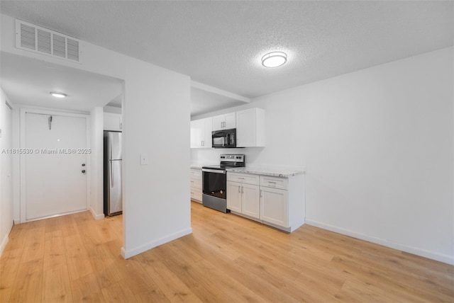 9601 Sunrise Lakes Blvd Unit 106, Sunrise, FL 33322 - kitchen with stainless steel appliances, a textured ceiling, white cabinetry, light wood-type flooring, and baseboards