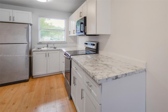 9601 Sunrise Lakes Blvd Unit 106, Sunrise, FL 33322 - kitchen with appliances with stainless steel finishes, a sink, white cabinets, light wood-style floors, and light stone countertops