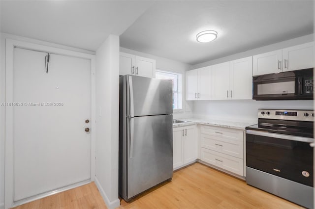 9601 Sunrise Lakes Blvd Unit 106, Sunrise, FL 33322 - kitchen with appliances with stainless steel finishes, light wood-type flooring, white cabinetry, and light countertops