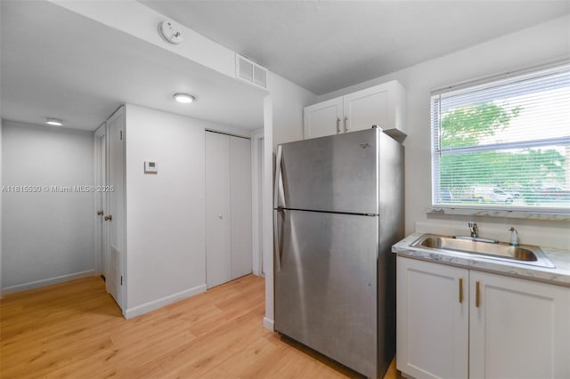 9601 Sunrise Lakes Blvd Unit 106, Sunrise, FL 33322 - kitchen with freestanding refrigerator, a sink, light wood-style flooring, white cabinets, and light countertops