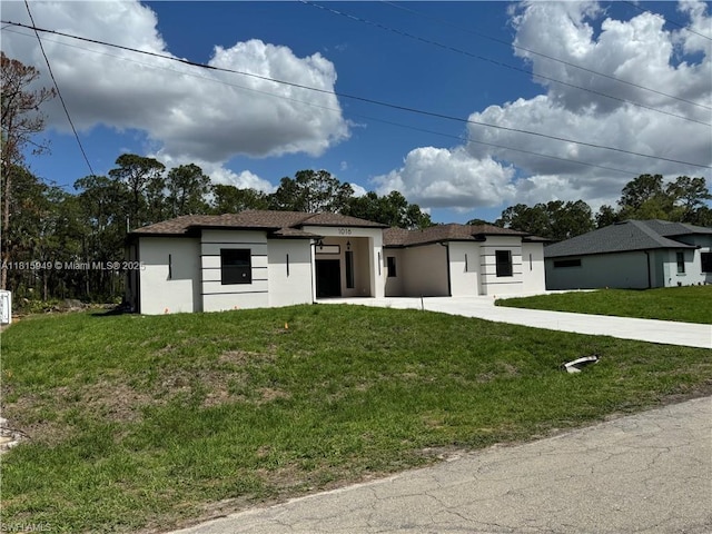 1016 Magnolia Ave, Lehigh Acres, FL 33974 - prairie-style house with stucco siding, a front yard, and concrete driveway