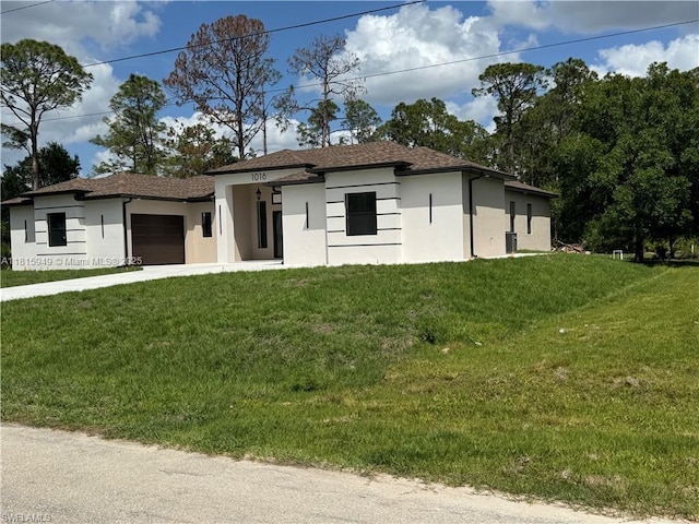 1016 Magnolia Ave, Lehigh Acres, FL 33974 - prairie-style house with stucco siding, a garage, a front yard, and driveway