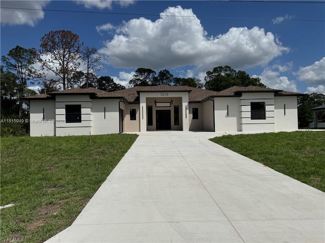 1016 Magnolia Ave, Lehigh Acres, FL 33974 - prairie-style house featuring concrete driveway, stucco siding, and a front yard