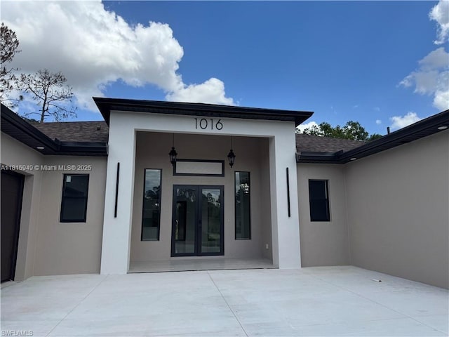 1016 Magnolia Ave, Lehigh Acres, FL 33974 - entrance to property with french doors, stucco siding, roof with shingles, and a patio