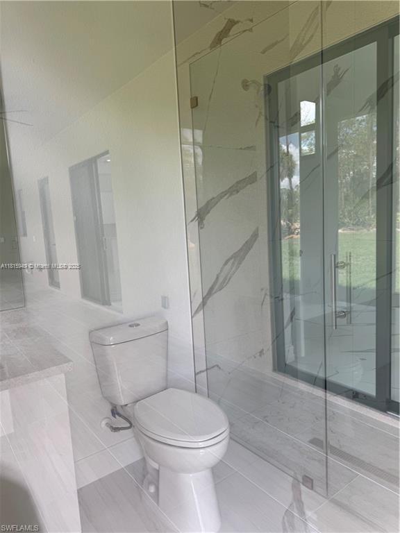 1016 Magnolia Ave, Lehigh Acres, FL 33974 - full bathroom with toilet, a marble finish shower, and tile patterned floors
