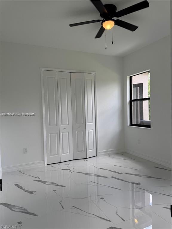 1016 Magnolia Ave, Lehigh Acres, FL 33974 - unfurnished bedroom featuring marble tiled floors, baseboards, a closet, and ceiling fan