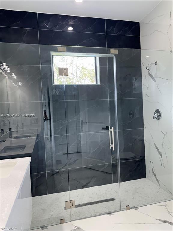 1016 Magnolia Ave, Lehigh Acres, FL 33974 - bathroom with double vanity, a marble finish shower, and marble finish flooring