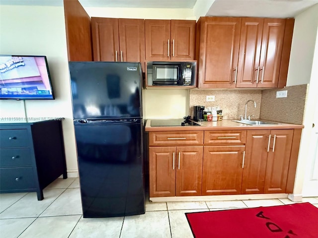 19201 Collins Ave Unit 242, Sunny Isles Beach, FL 33160 - kitchen with black appliances, a sink, backsplash, light tile patterned floors, and brown cabinetry