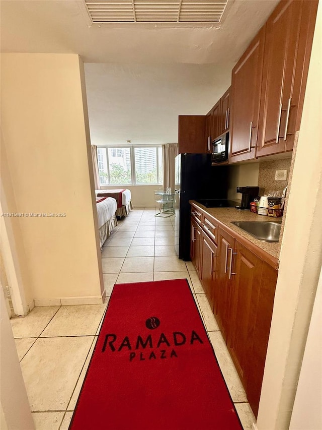 19201 Collins Ave Unit 242, Sunny Isles Beach, FL 33160 - kitchen with light tile patterned flooring, black microwave, a sink, and light countertops