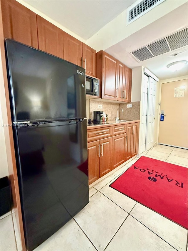 19201 Collins Ave Unit 242, Sunny Isles Beach, FL 33160 - kitchen with black appliances, light tile patterned floors, a sink, light countertops, and decorative backsplash