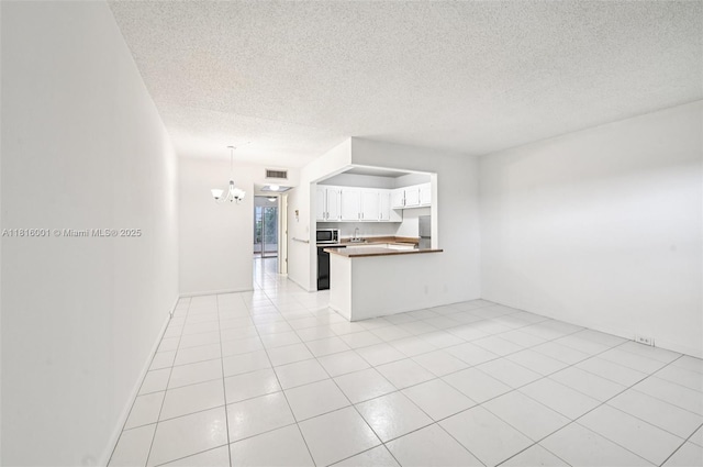 4007 Durham A 4007, Deerfield Beach, FL 33442 - kitchen featuring a chandelier, open floor plan, a peninsula, stainless steel microwave, and a textured ceiling