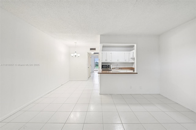 4007 Durham A 4007, Deerfield Beach, FL 33442 - unfurnished living room featuring a chandelier, a sink, a textured ceiling, and light tile patterned floors