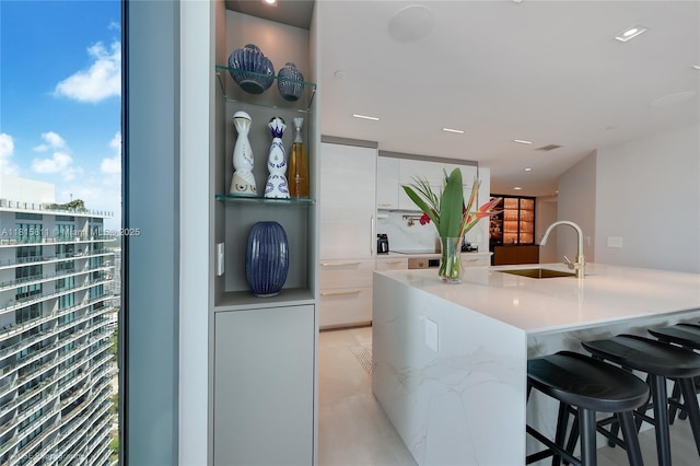650 NE 32nd St Unit 4701, Miami, FL 33137 - kitchen featuring a sink, modern cabinets, white cabinets, light countertops, and a kitchen bar