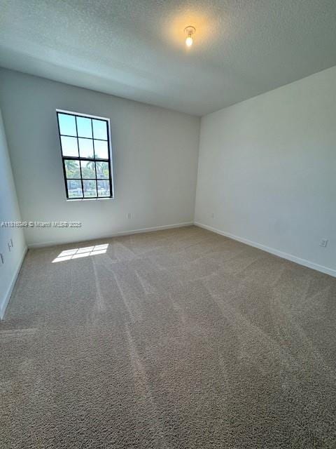 605 NW 6th Ter, Florida City, FL 33034 - spare room featuring a textured ceiling, carpet, and baseboards