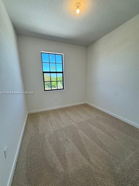 605 NW 6th Ter, Florida City, FL 33034 - empty room with light colored carpet, baseboards, and a textured ceiling
