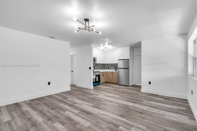19330 NE 2nd Ave, Miami, FL 33179 - unfurnished living room with a chandelier, light wood-style floors, and baseboards