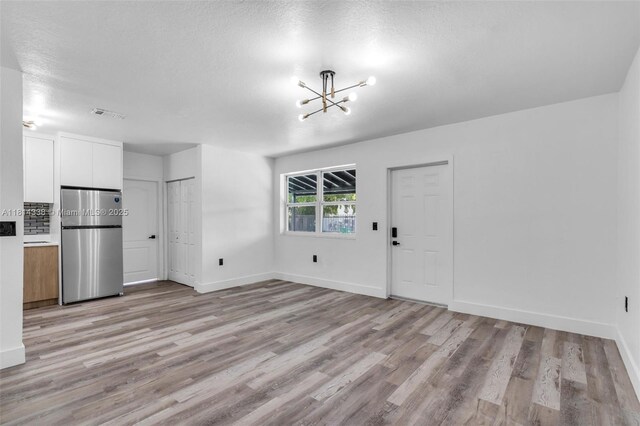 19330 NE 2nd Ave, Miami, FL 33179 - unfurnished living room featuring light wood-style flooring, a chandelier, and baseboards