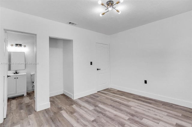 19330 NE 2nd Ave, Miami, FL 33179 - unfurnished bedroom featuring light wood finished floors, a chandelier, baseboards, a sink, and ensuite bath