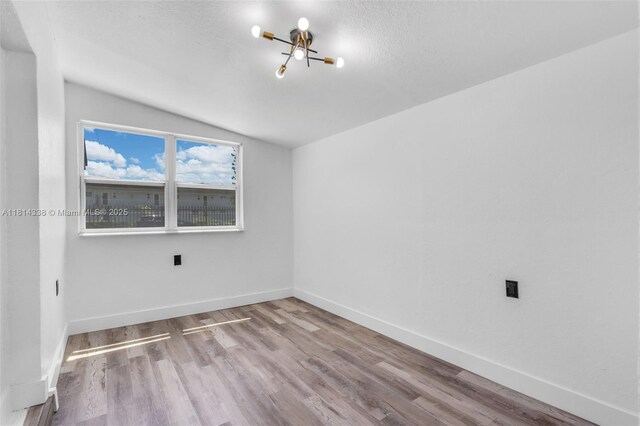 19330 NE 2nd Ave, Miami, FL 33179 - unfurnished room with a chandelier, lofted ceiling, wood finished floors, and baseboards