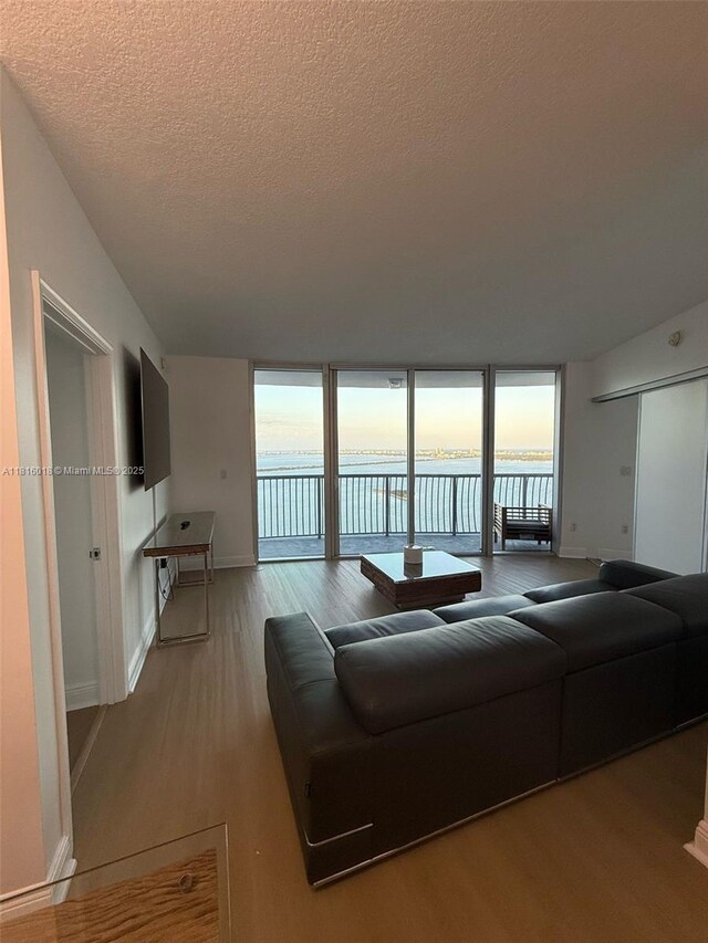 1750 N Bayshore Dr Unit 5401, Miami, FL 33132 - living area with light wood-style floors, a textured ceiling, a wall of windows, and baseboards