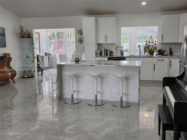 117 SW Fairview Ave, Port St Lucie, FL 34983 - kitchen with a sink, healthy amount of natural light, light stone counters, and recessed lighting