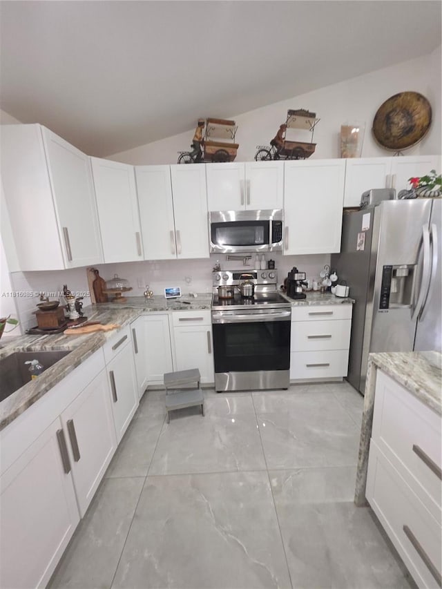 117 SW Fairview Ave, Port St Lucie, FL 34983 - kitchen with appliances with stainless steel finishes, white cabinets, lofted ceiling, and light stone countertops