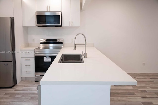 251 NW 76th Ave Unit 208, Margate, FL 33063 - kitchen featuring appliances with stainless steel finishes, a sink, light wood-style flooring, and a peninsula