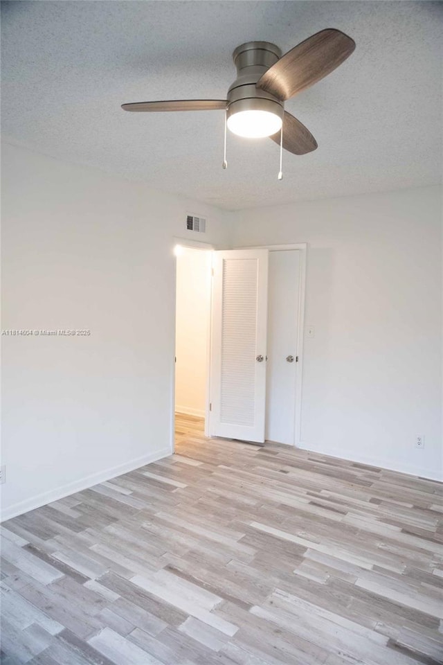 251 NW 76th Ave Unit 208, Margate, FL 33063 - spare room featuring light wood finished floors, ceiling fan, baseboards, and a textured ceiling