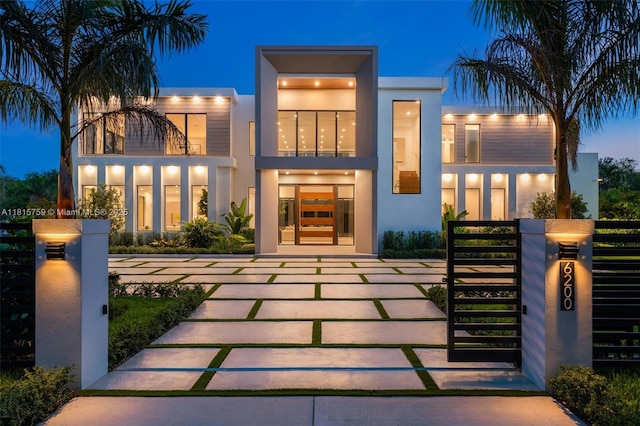 6200 Moss Ranch Rd, Pinecrest, FL 33156 - view of front of house featuring stucco siding, a gate, a fenced front yard, and a balcony