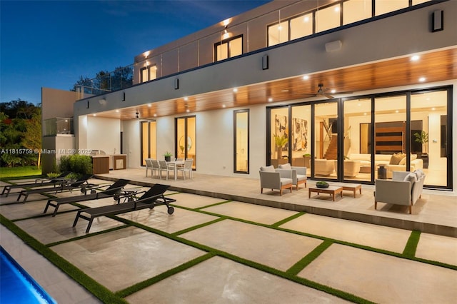 6200 Moss Ranch Rd, Pinecrest, FL 33156 - back of house at night with outdoor lounge area, a patio, stucco siding, and outdoor dining area